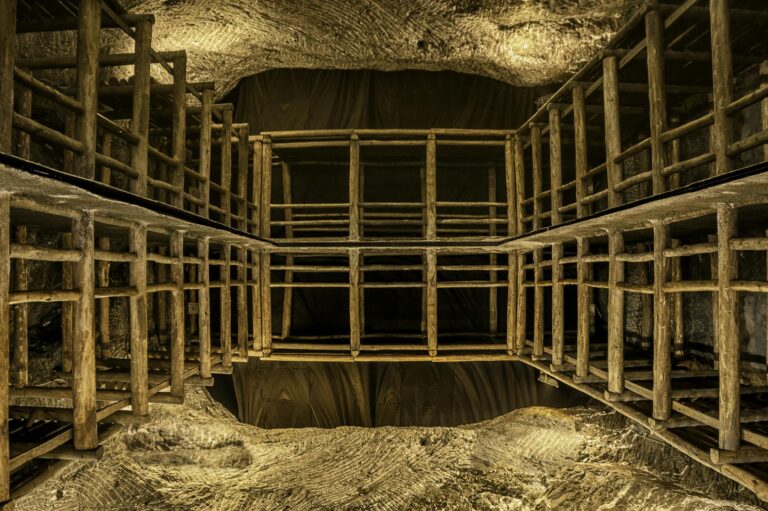 Intricate wooden scaffolding structure inside a well-lit underground cave or mine shaft.